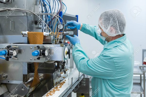 Pharmaceutical technician in sterile environment working with equipment at pharmacy industry